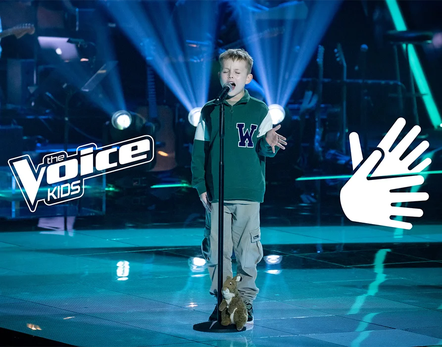 Ein Junge singt auf einer in blau-grünem Licht erleuchteten Bühne in ein Mikrofon. Daneben steht ein Stofftier-Eichhörnchen. Das Logo "the Voice Kids" ist im Bild links eingeblendet. Rechts eine Grafik die zwei Hände zeigt. (Foto)